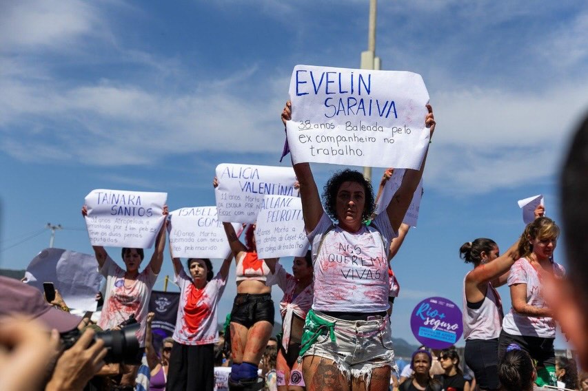 Mulheres em Copacabana seguram cartazes com nomes de vítimas de feminicídio