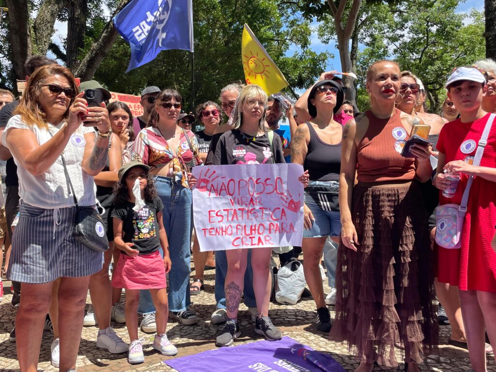 Grupo de pessoas em ato com cartaz contra a violência de gênero